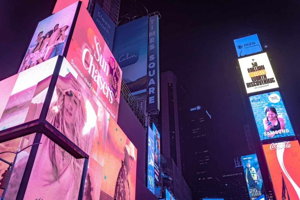 Illuminated digital billboards at night, illustrating the Mubadala Capital Clear Channel Outdoor acquisition
